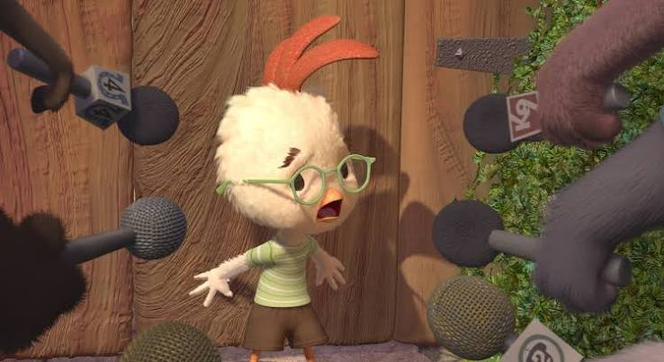 Chicken Little, mouth open, surrounded by a crowd of microphones